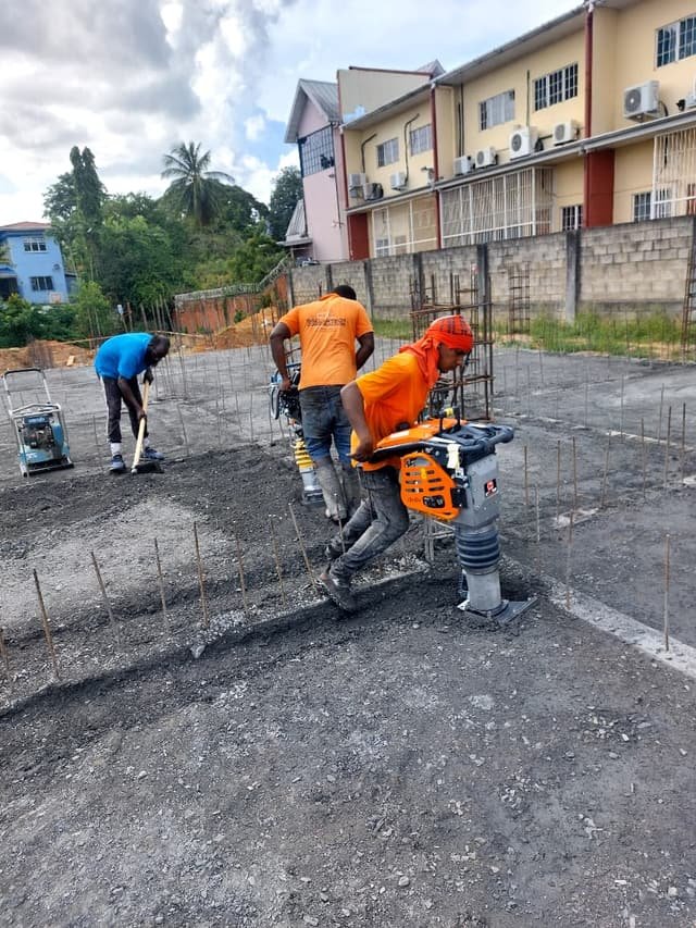A crew compacting a foundation base with hired rammer and plate compactors